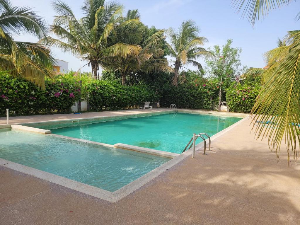 a large swimming pool with palm trees in the background at Villa oasis n°5 in Gandigal