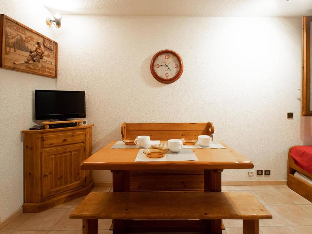 una camera con tavolo in legno e orologio sul muro di Appartement Valmorel, 1 pièce, 4 personnes - FR-1-291-814 a Valmorel