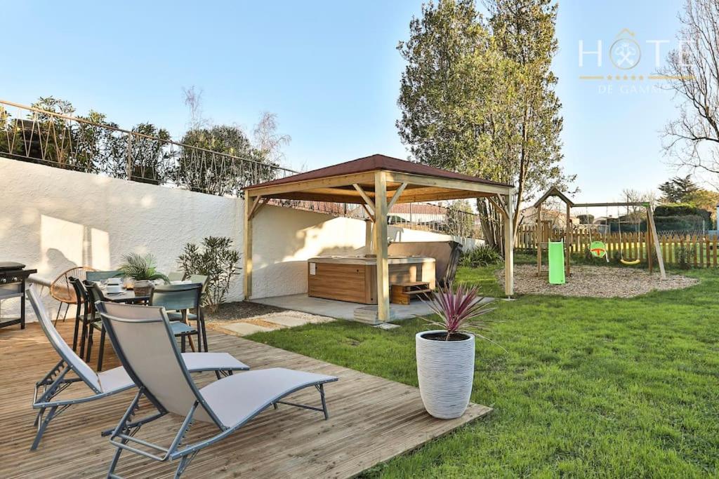 una terraza de madera con cenador en un patio en Logement de standing avec jacuzzi, classé 4* en LʼÎle-dʼOlonne