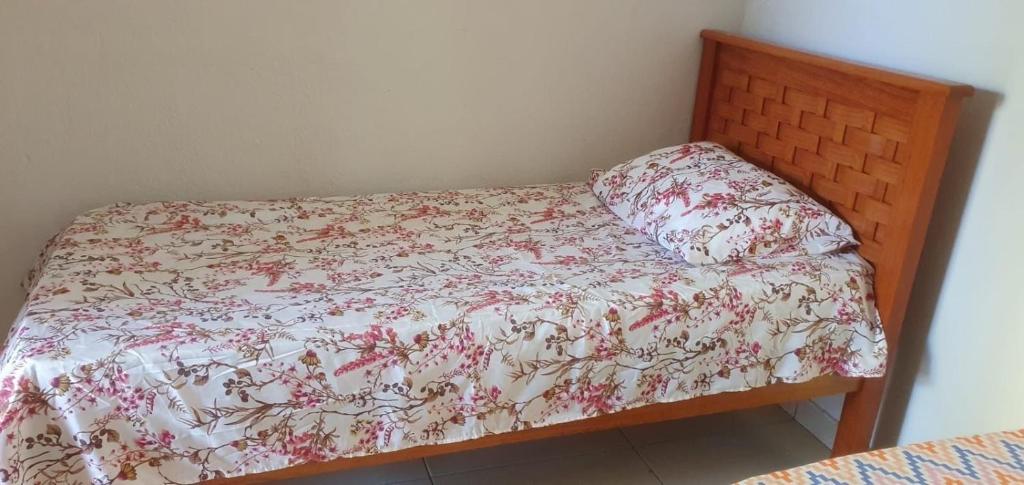 a bed with a floral comforter and a pillow at TrevizZo Genipabu Natal! in Natal