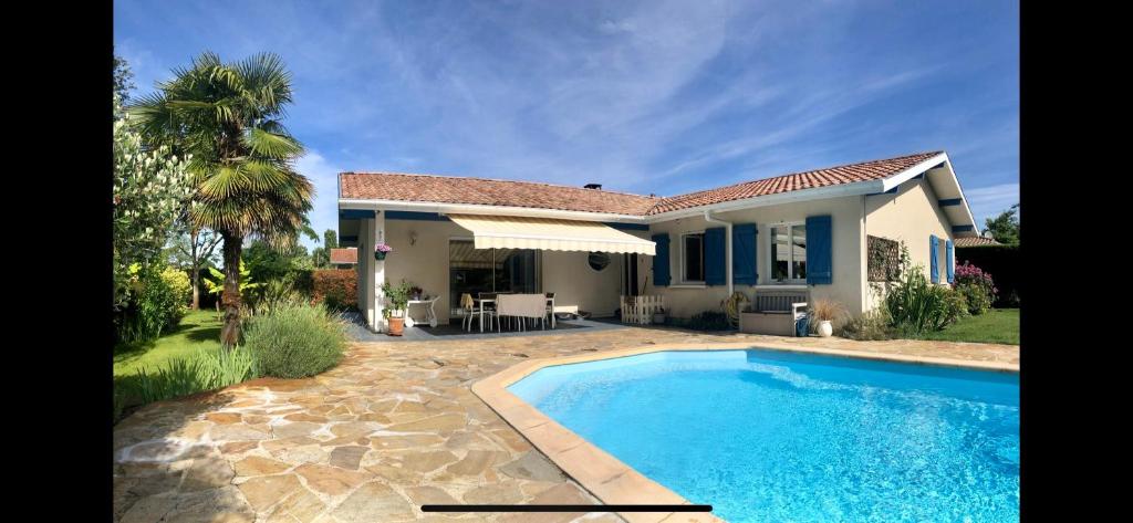 una villa con piscina frente a una casa en Villa Naturéa, en Messanges