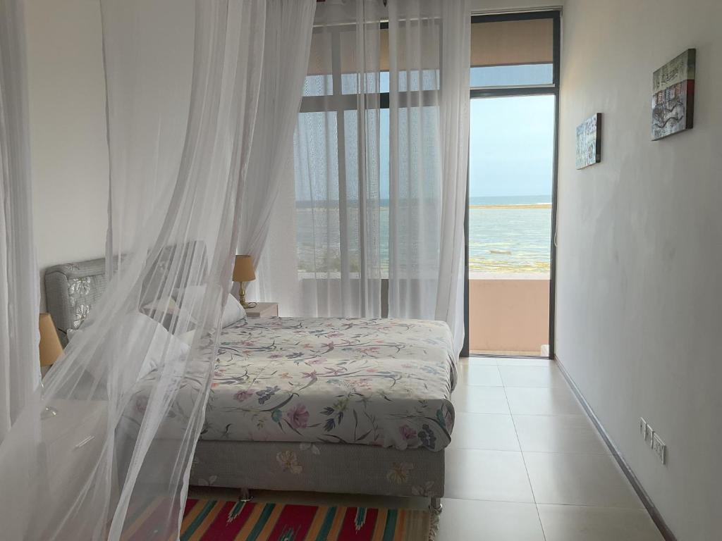 1 dormitorio con cama y vistas al océano en Casa di Kasa, en Vipingo