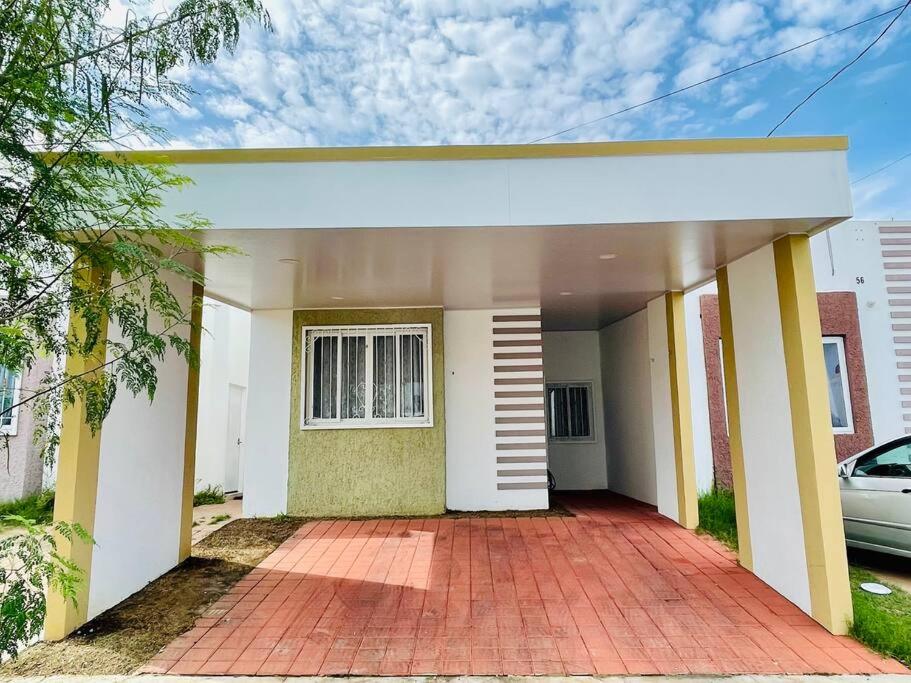 una casa bianca e gialla con un vialetto di mattoni di Moderna casa amueblada en residencial privada a San Miguel