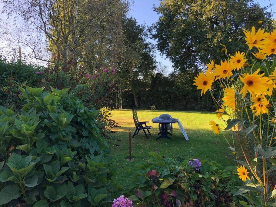 einen Garten mit einem Tisch und einem Stuhl im Gras in der Unterkunft Longère chaleureuse et familiale - 3 chambres in Limerzel
