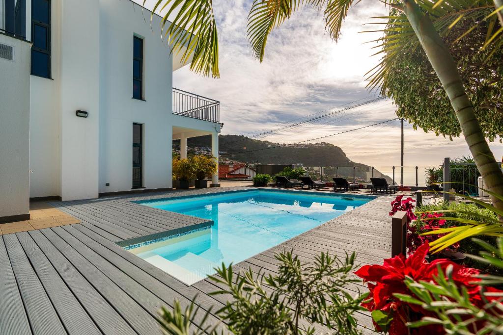 a house with a swimming pool and a wooden deck at Villa Nunes, Big Holiday house with private pool in Calheta