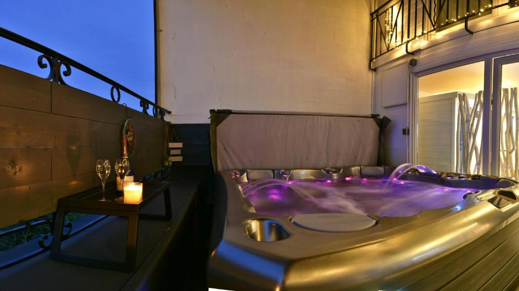 uma casa de banho com uma banheira com uma vela e uma mesa em Le LOFT, MoonLOVE, Jacuzzi et sauna privatifs sur terrasse, 120m2 em Jarville-la-Malgrange