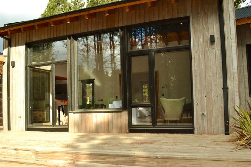 圣马丁德洛斯Chapelco Golf - Cabaña a Estrenar的建筑物上的一大片玻璃窗