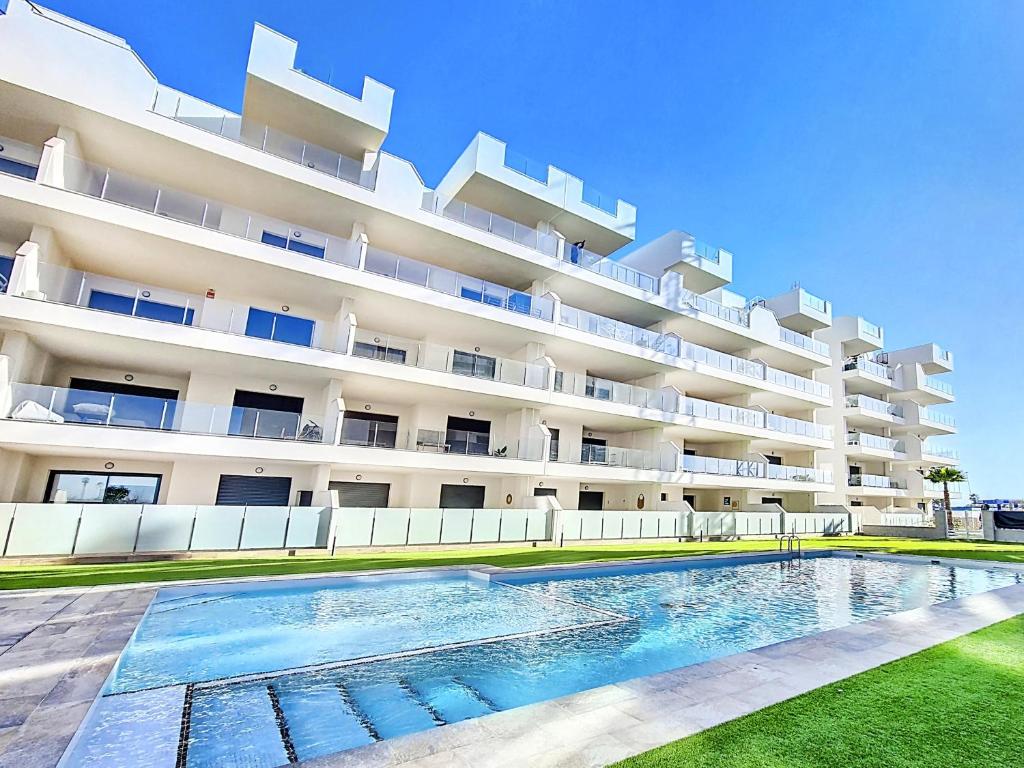 a hotel with a swimming pool in front of a building at Los Alcazares Velapi - 0510 in San Javier