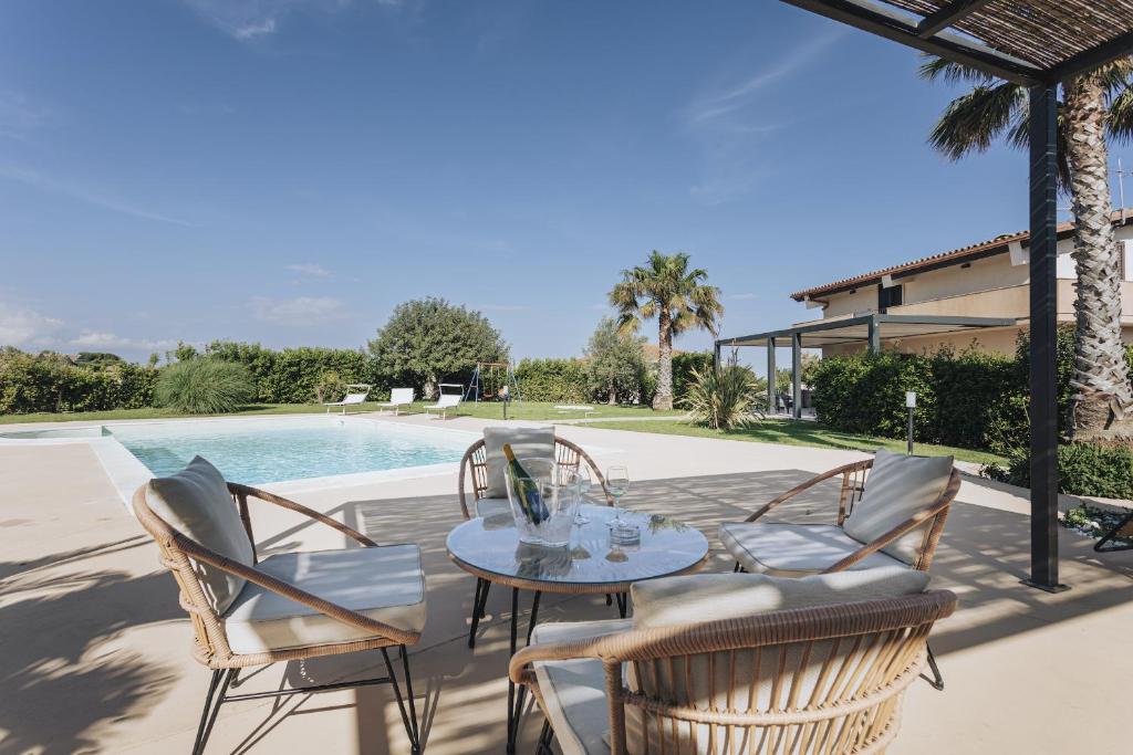 a patio with a table and chairs next to a pool at Isula Relax - IsulaTravel in Modica