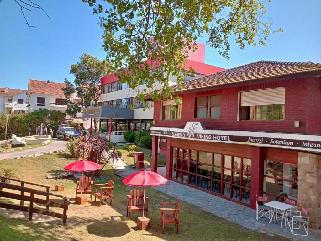 a building with tables and umbrellas in front of it at San Remo Viking Hotel in Pinamar