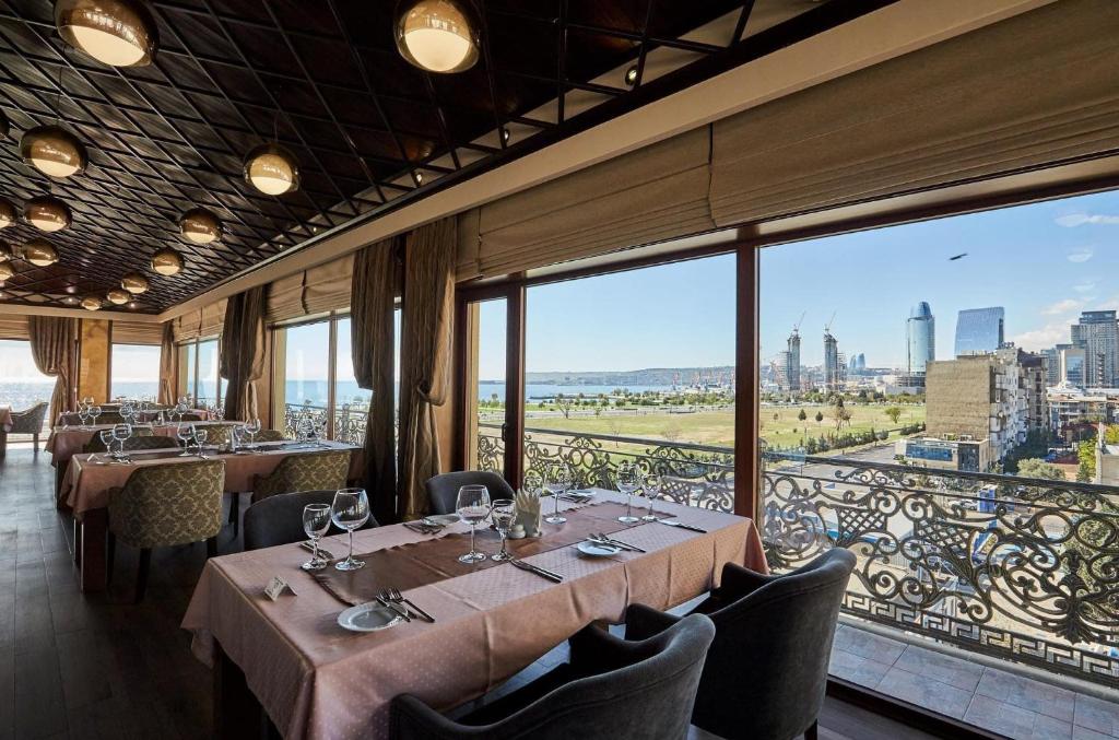 a restaurant with tables and chairs and a large window at Boulevard Side Hotel in Baku