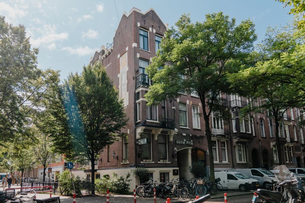 un grand bâtiment en briques avec des arbres devant lui dans l'établissement Hotel Fita, à Amsterdam