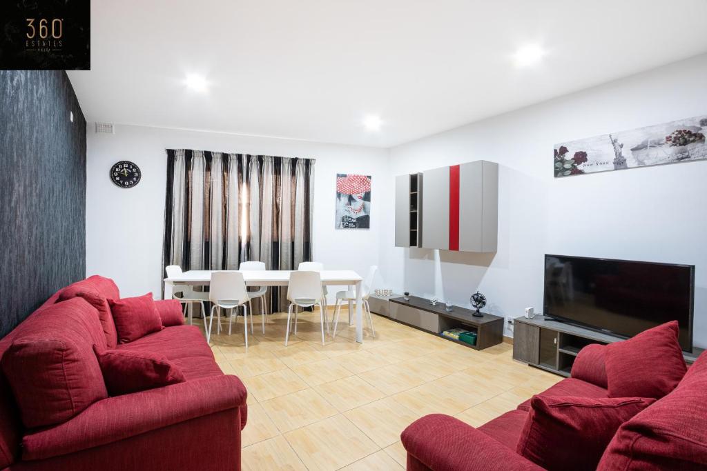 een woonkamer met twee rode banken en een eetkamer bij A Large house in central pieta with BBQ & Terrace by 360 Estates in Tal-Pietà