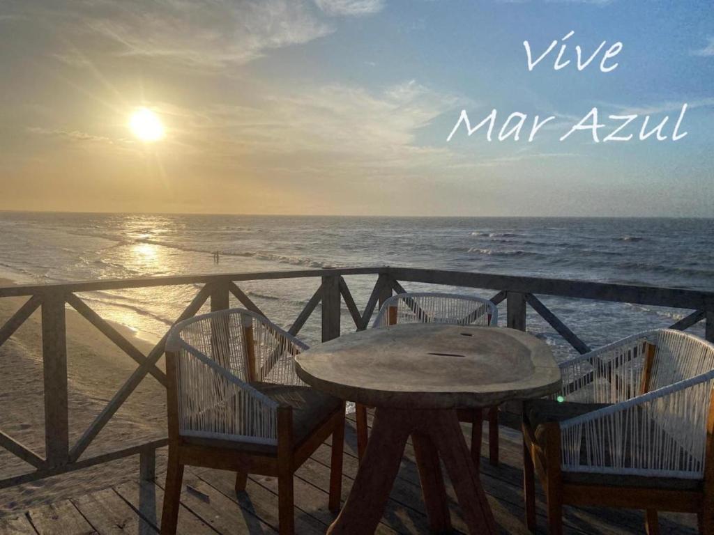 uma mesa e cadeiras num cais com o oceano em Mar Azul - Playa y Turismo em Camarones