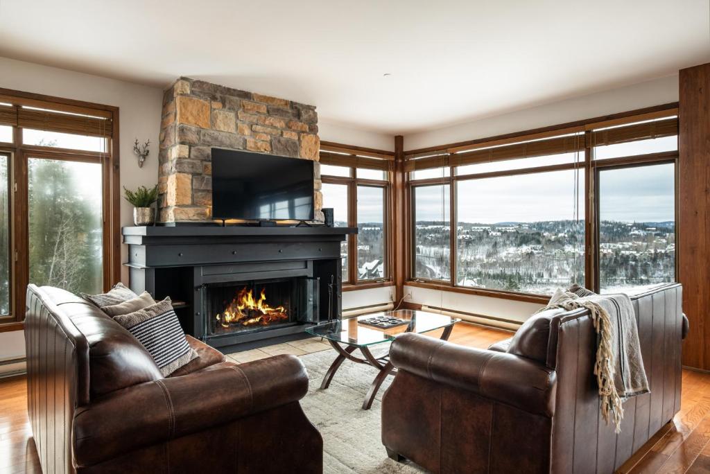 a living room with two chairs and a fireplace at Altitude 172-8/On Village with Astonishing VIEWS in Mont-Tremblant
