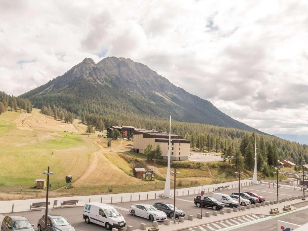 - un parking avec des voitures garées devant une montagne dans l'établissement Studio confortable pour 4 à Montgenèvre avec casier à skis, proche commodités. - FR-1-330D-96, à Montgenèvre