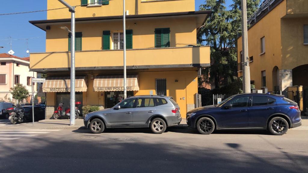 due auto parcheggiate in una strada di fronte a un edificio di Casa Francia Emilia Levante a Bologna