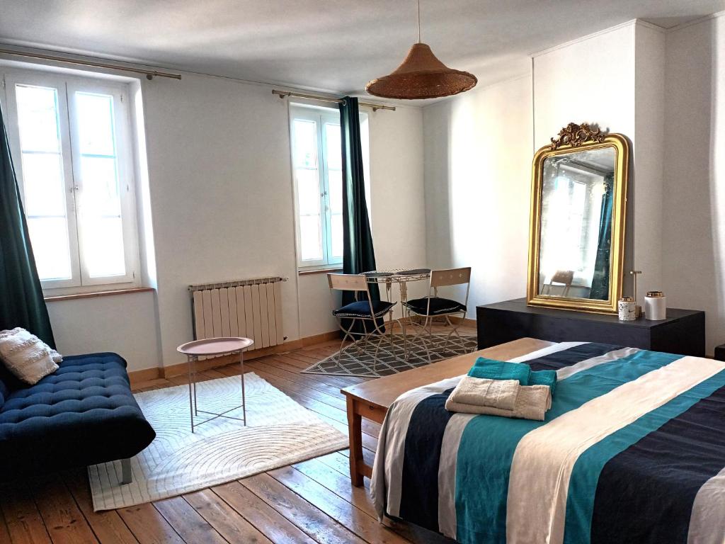 1 dormitorio con cama, espejo y silla en Le Relais du Fraysse - Chambres d'hôtes, en Le Fraysse