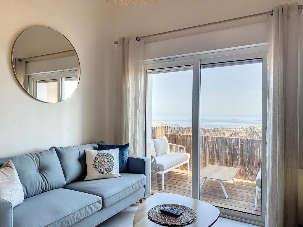 un salon avec un canapé bleu et un miroir dans l'établissement Monticello duplex vue exceptionnelle mer et montagne, à Monticello