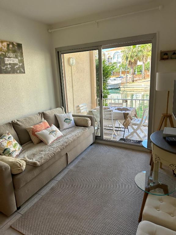 un salon avec un canapé et une porte coulissante en verre dans l'établissement Marina des quilles magnifiqueT2 avec terrasse, à Sète