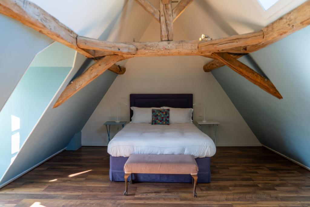 a bedroom in the attic with a bed and a stool at 1 Rue Pasquet - Double room in main house in Beaumont-du-Périgord