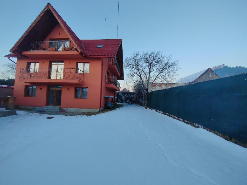dom w śniegu obok płotu w obiekcie Casa Diana Rasnov w mieście Râșnov