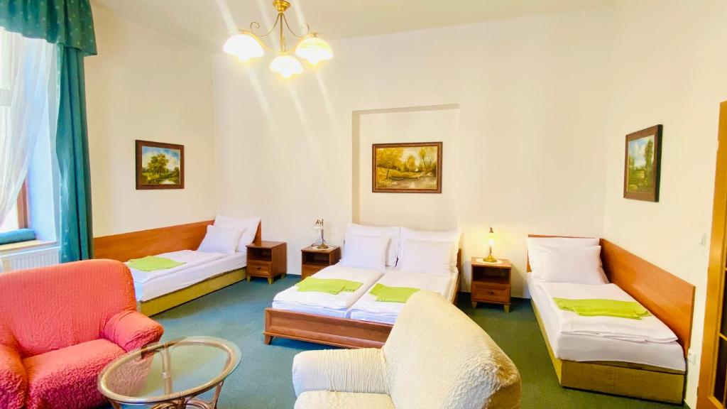 Cette chambre comprend deux lits, un canapé et une chaise. dans l'établissement Penzion Černý Kůň, à Hradec Králové