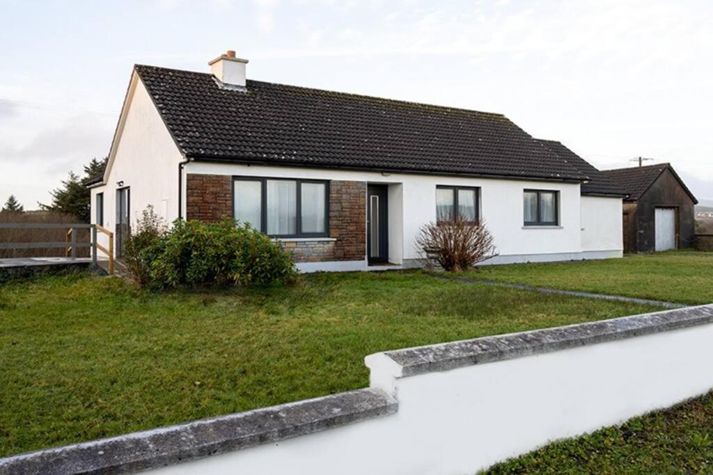 een wit huis met een groene tuin bij Doolin Getaway. in Lisdoonvarna