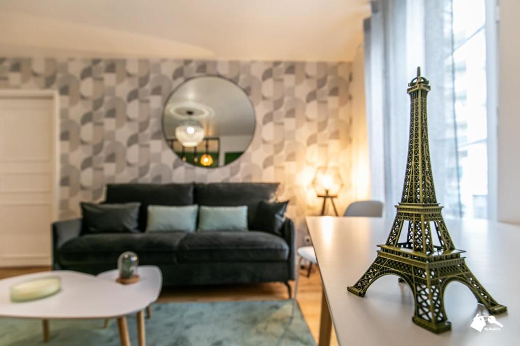 a living room with a black couch and a eiffel tower at MBA Splendide Appart - Wilson 1 - Mairie de Montreuil in Montreuil