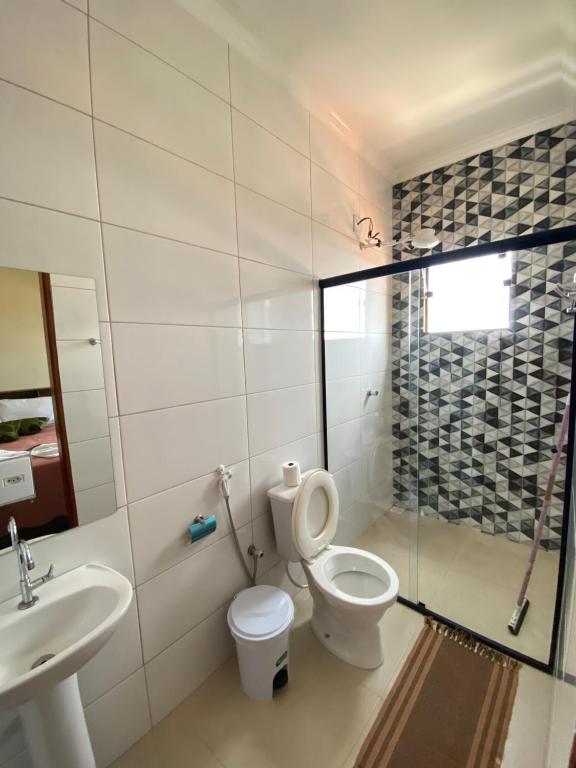 La salle de bains est pourvue de toilettes, d'un lavabo et d'une douche. dans l'établissement Pousada Véu de Noiva, à São Thomé das Letras