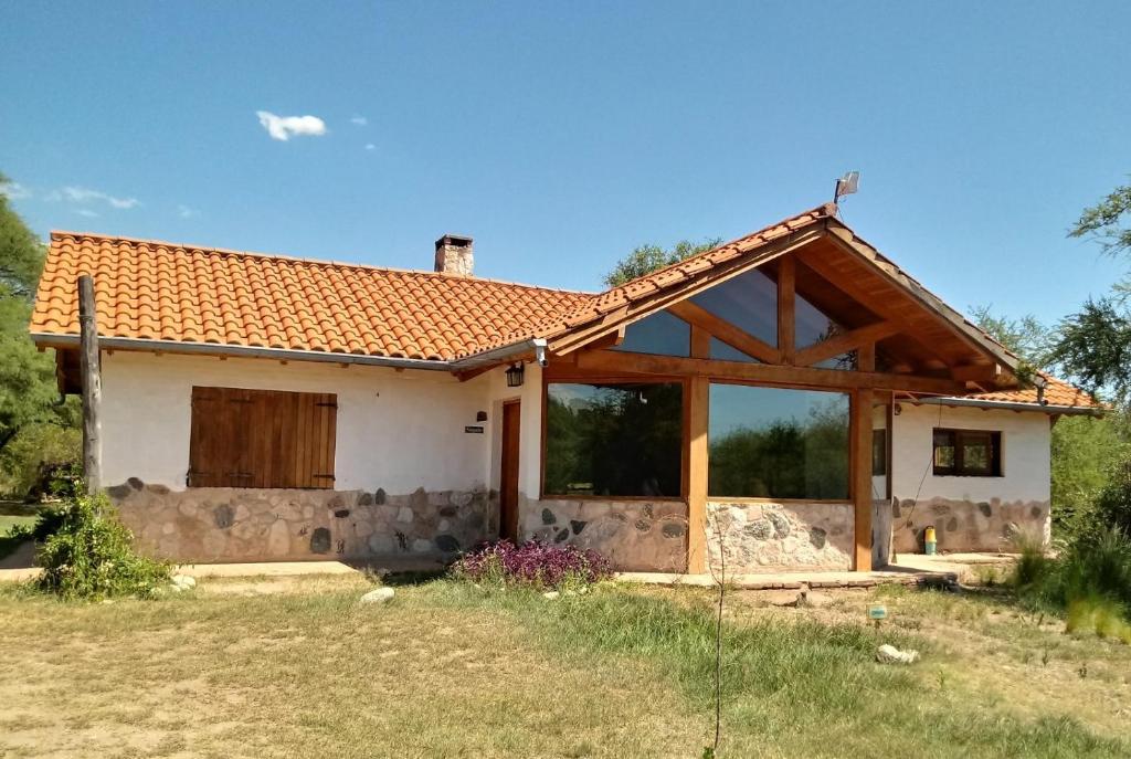 uma pequena casa branca com um telhado vermelho em Atardecida em Villa de Las Rosas