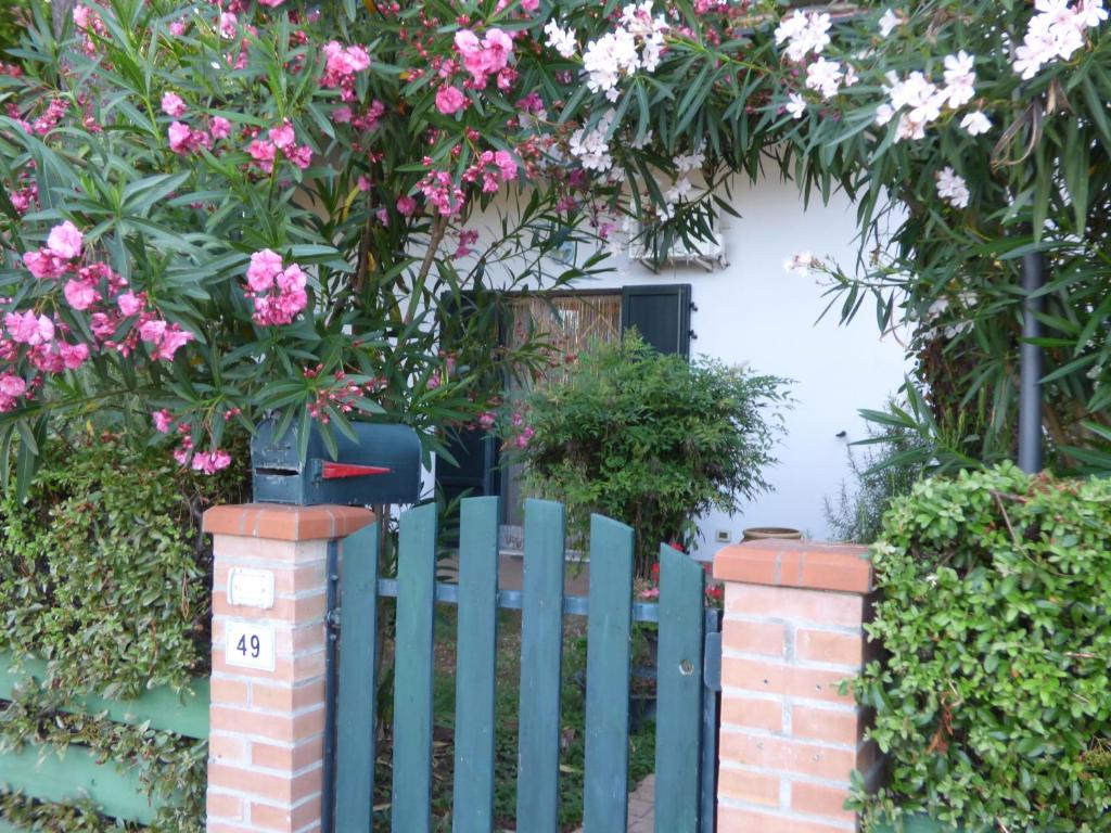 a blue fence with pink flowers in front of a house at B&B Amici Miei in Marina Romea