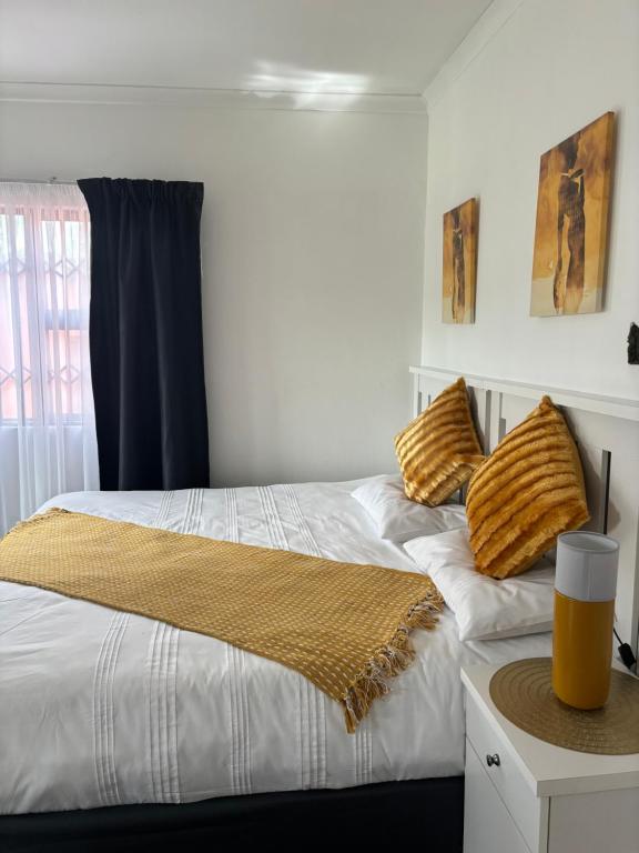 1 dormitorio con 2 camas con almohadas amarillas en TT’s self-catering apartments, en Qumbu
