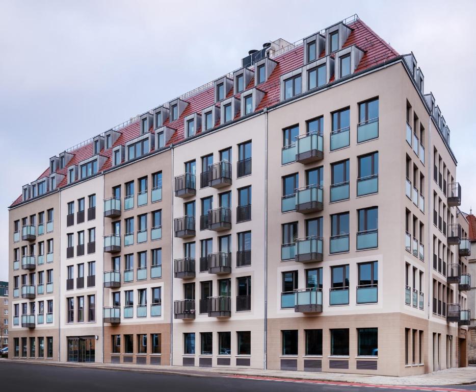 un gran edificio blanco con techo rojo en prizeotel Dresden-Mitte, en Dresden