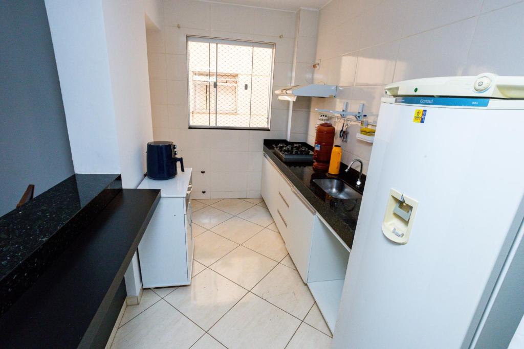 a kitchen with a white refrigerator and a sink at Aconchego Veredas II in Viçosa