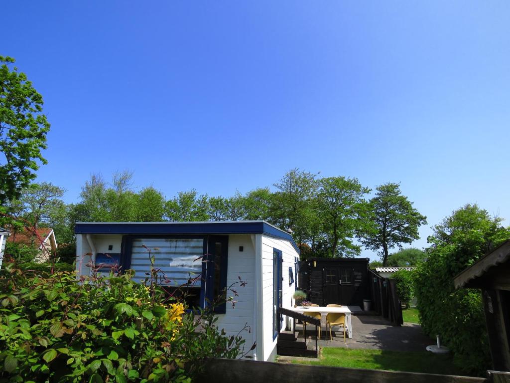 een kleine witte schuur met een tafel in een tuin bij Chalet Seazon R23 in Buren