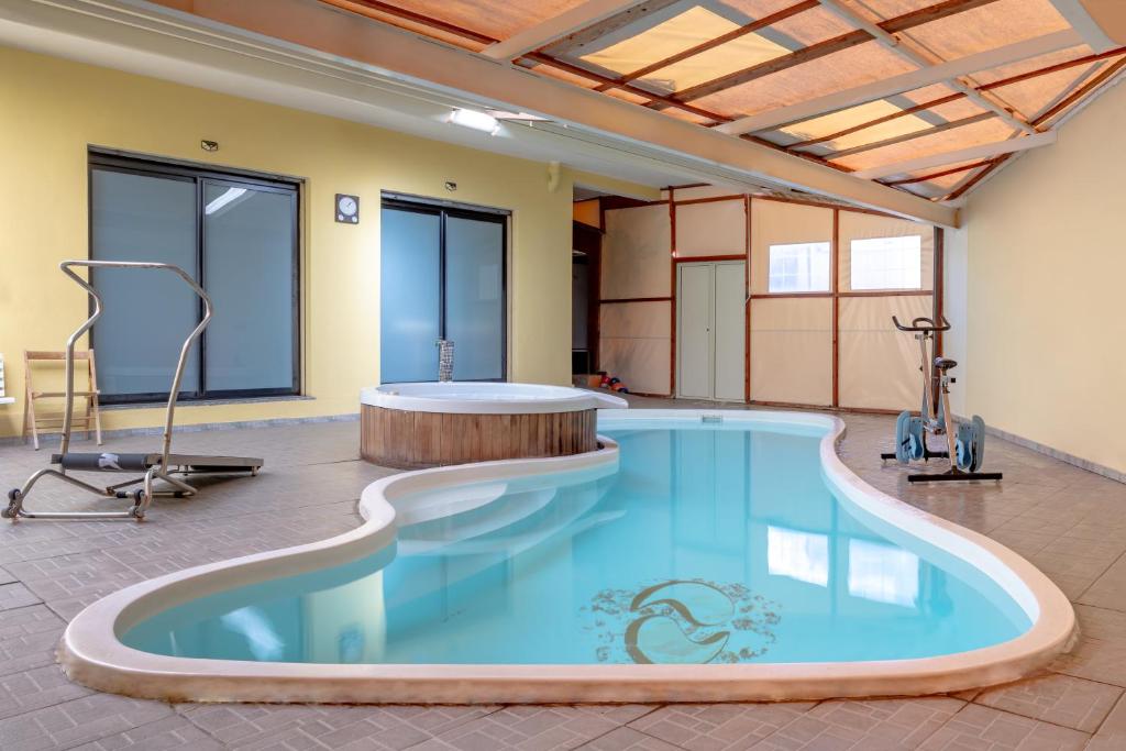een groot zwembad in een kamer met een fitnessruimte bij Holos Apartment in Capoterra