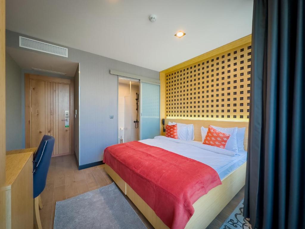 a bedroom with a large bed with a red blanket at Mihman Hotel in Tuzla