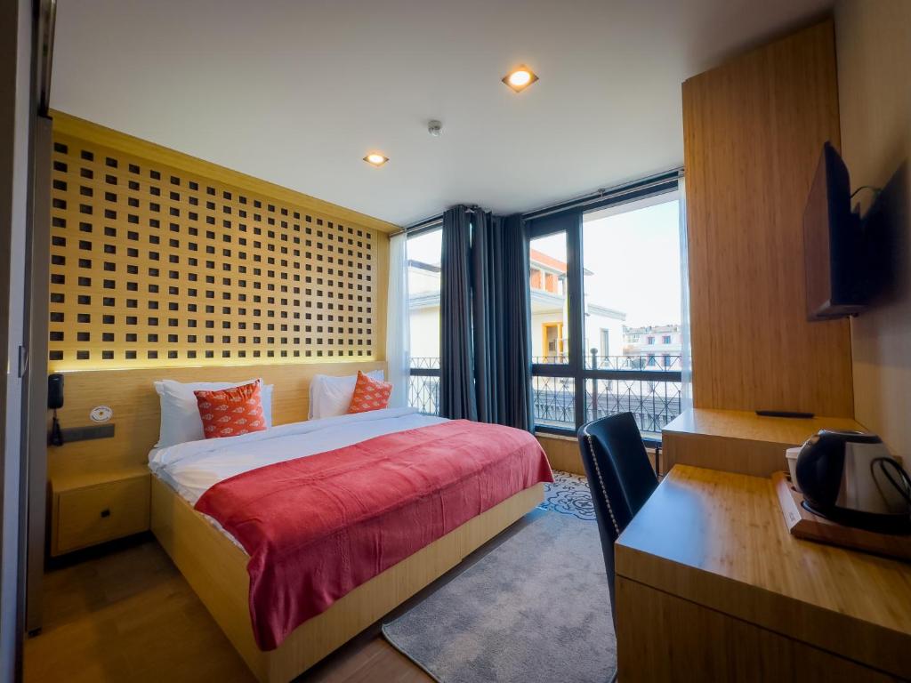a bedroom with a bed and a desk and a window at Mihman Hotel in Tuzla