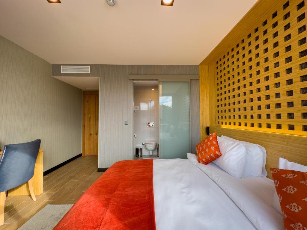 a bedroom with a large white bed with orange pillows at Mihman Hotel in Tuzla