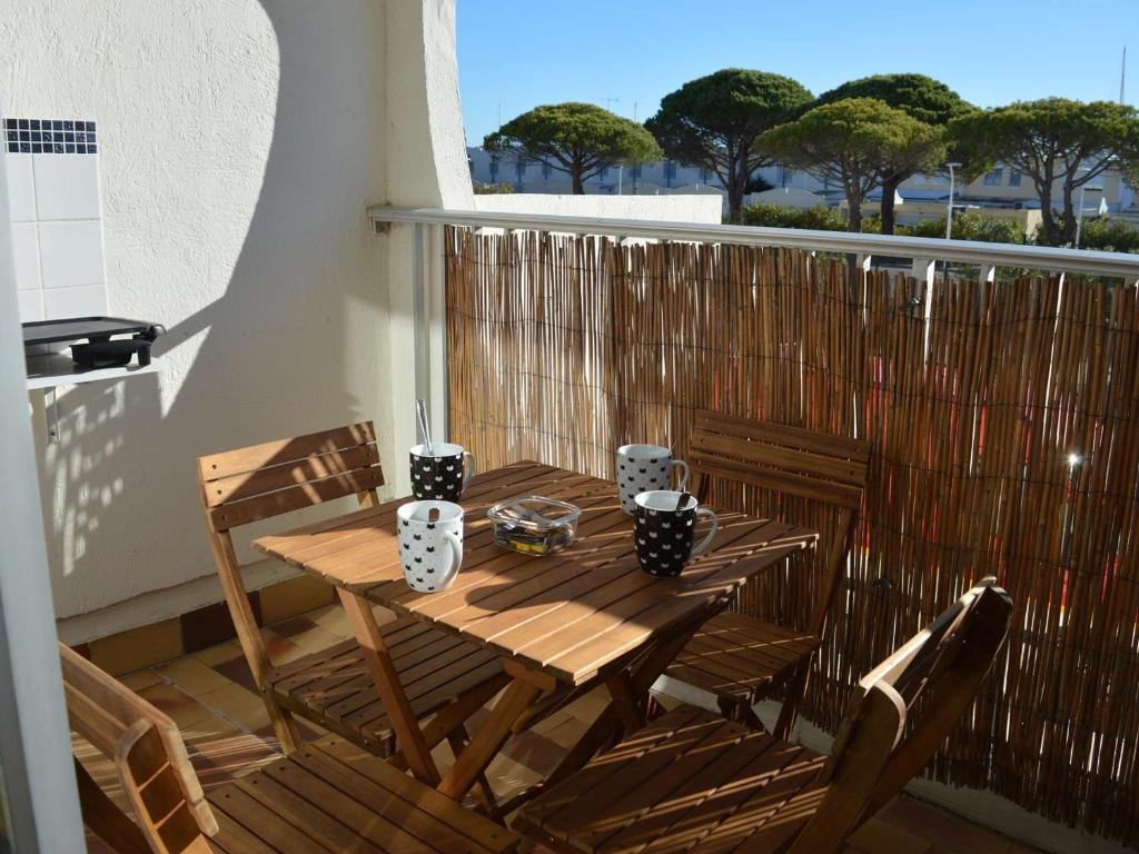une table et des chaises en bois sur un balcon dans l'établissement Studio Cabine lumineux, loggia & plancha à Port Camargue, 4 couchages, ménage inclus - FR-1-250-161, au Grau-du-Roi