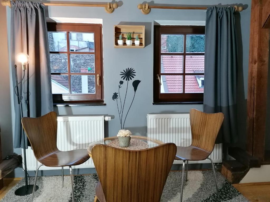 a dining room with a table and chairs and windows at Guest House Olšakovský in Český Krumlov