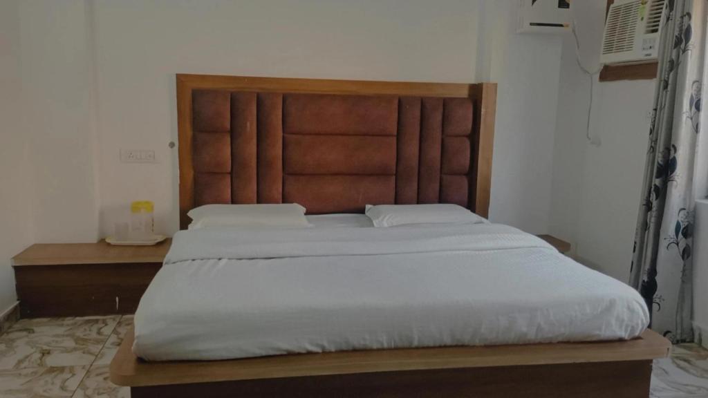 a bedroom with a large bed with a wooden headboard at The relax in hotel in Katra