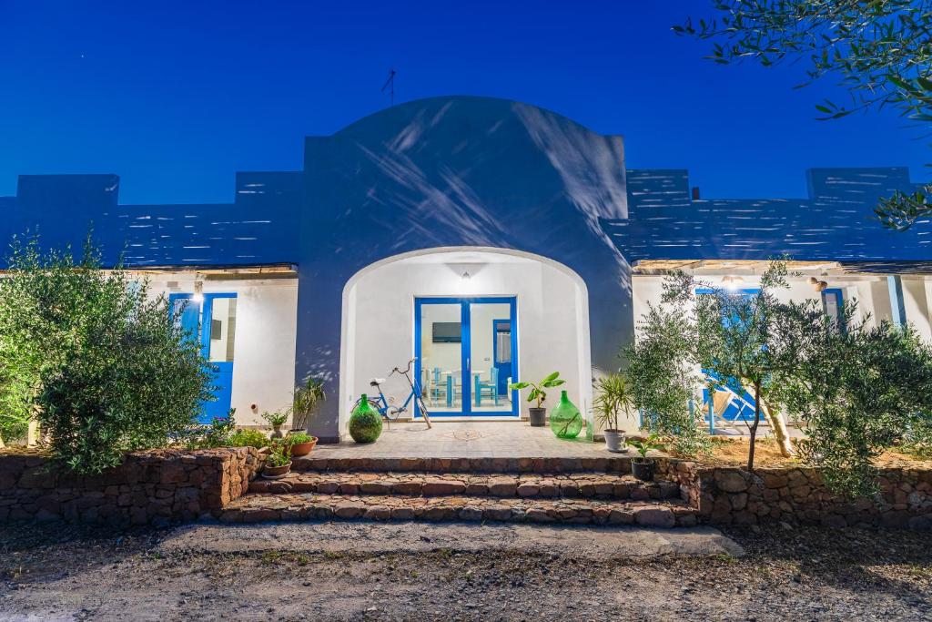 uma casa branca com uma porta azul e escadas em B&B S'Incantu em SantʼAnna Arresi