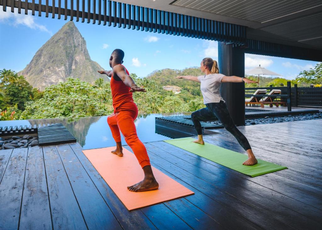 Due persone che fanno yoga sui materassini di fronte alla piscina di Rabot Hotel From Hotel Chocolat a Soufriere