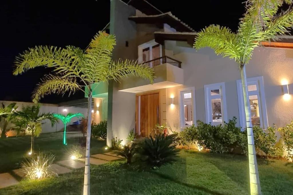 una casa con palmeras en el patio por la noche en Recanto dos Canários - Búzios en Búzios