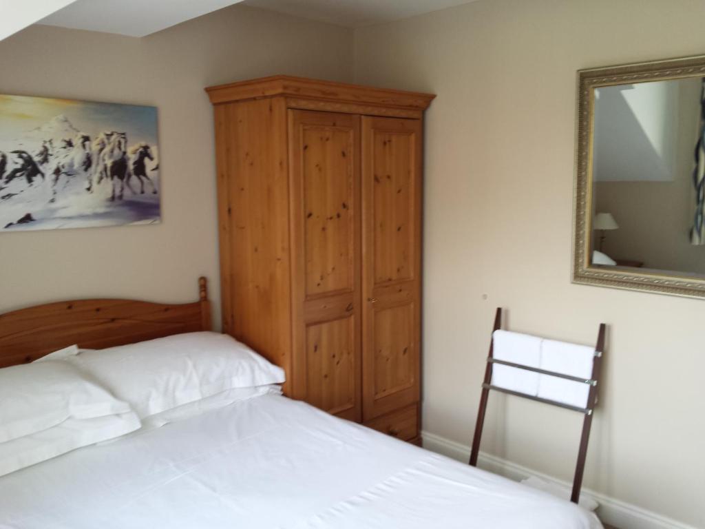 a bedroom with a bed and a wooden cabinet and a mirror at Glenade in Bath