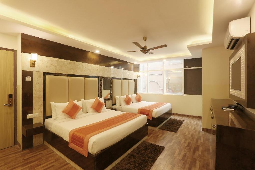 a hotel room with two beds and a ceiling fan at Plazzo Prime Plaza in New Delhi