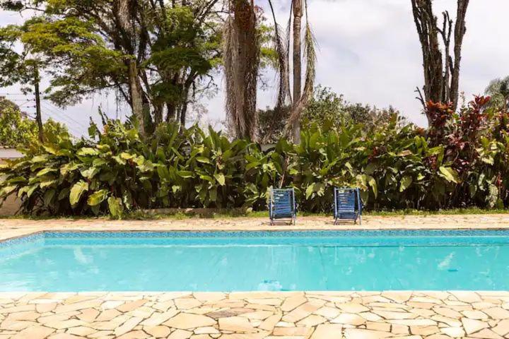 due sedie blu sedute accanto alla piscina di chácara paraíso tropical a Biritiba-Mirim