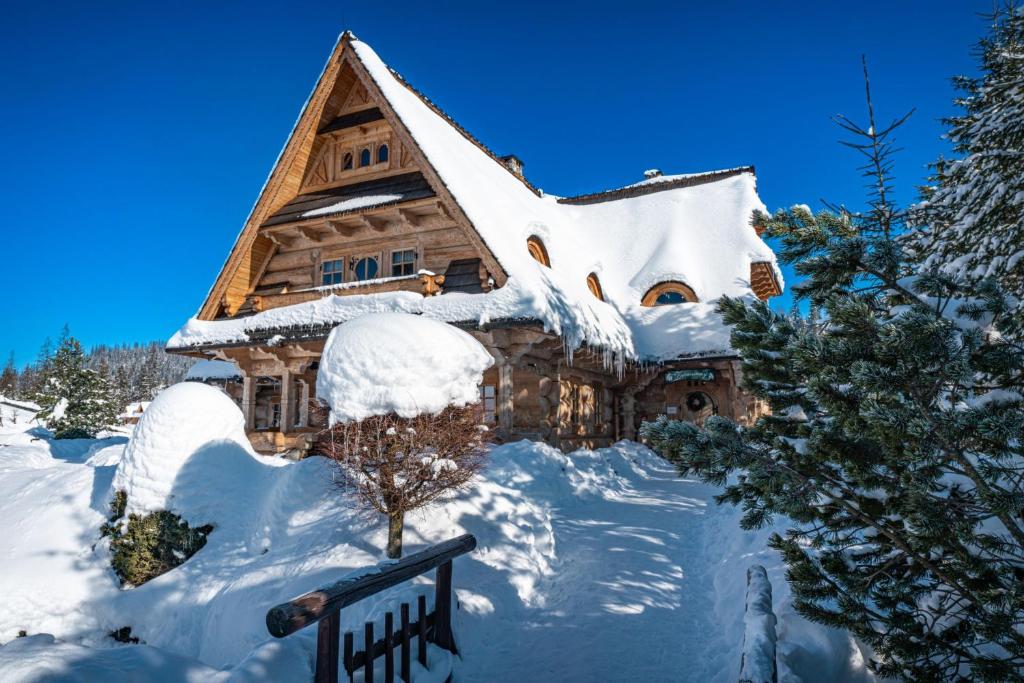 una casa de madera cubierta de nieve en Tatrzański Bór Apartamenty, en Małe Ciche